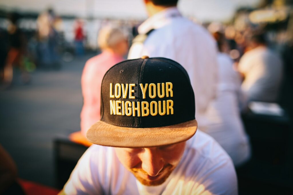 living faith, man wearing black cap with love your neighbour print during daytime